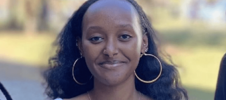 Smiling person with hoop earrings outdoors.
